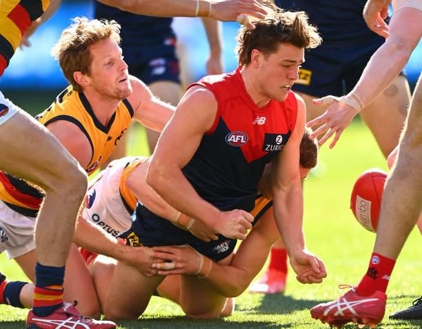 Tom Sparrow of the Demons handballs whilst being tackled by Rory Sloane of the Crows during the round 22 AFL match between Melbourne Demons and...