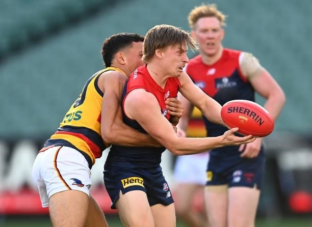 Charlie Spargo of the Demons handballs whilst being tackled during the round 22 AFL match between Melbourne Demons and Adelaide Crows at Melbourne...