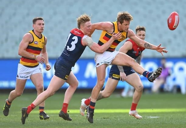 Rory Sloane of the Crows kicks whilst being tackled by Clayton Oliver of the Demons during the round 22 AFL match between Melbourne Demons and...