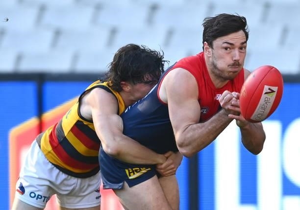 Michael Hibberd of the Demons handballs whilst being tackled by Ned McHenry of the Crows during the round 22 AFL match between Melbourne Demons and...
