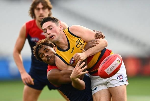 Chayce Jones of the Crows handballs whilst being tackled by Kysaiah Pickett of the Demons during the round 22 AFL match between Melbourne Demons and...