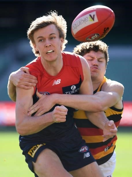 James Jordan of the Demons handballs whilst being tackled by Harry Schoenberg of the Crows during the round 22 AFL match between Melbourne Demons and...