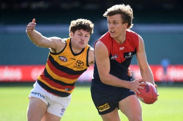James Jordan of the Demons handballs whilst being tackled by Harry Schoenberg of the Crows during the round 22 AFL match between Melbourne Demons and...