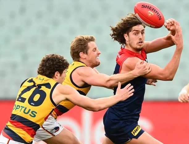 Luke Jackson of the Demons handballs whilst being tackled by Rory Sloane of the Crows during the round 22 AFL match between Melbourne Demons and...