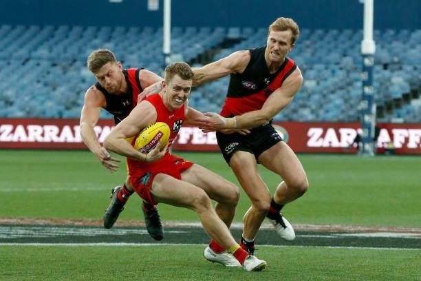 Jayden Laverde and James Stewart of the Bombers tackles Jacob Townsend of the Suns during the round 22 AFL match between Gold Coast Suns and Essendon...