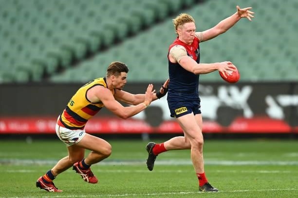 Clayton Oliver of the Demons kicks whilst being tackled by Ben Keays of the Crows during the round 22 AFL match between Melbourne Demons and Adelaide...