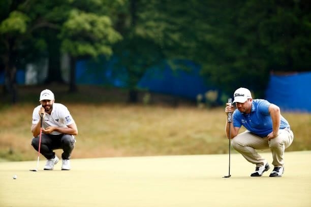 Adam Hadwin of Canada and Ben Taylor of England line up their putts on the first green during the final round of the Wyndham Championship at...