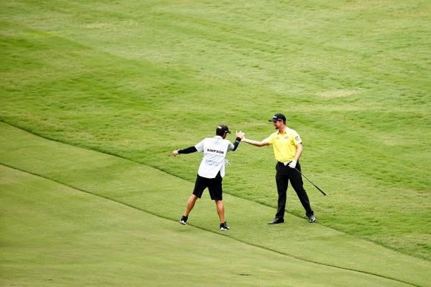 Webb Simpson of the United States celebrates with caddie Paul Tesori after holing out from the 11th fairway during the final round of the Wyndham...