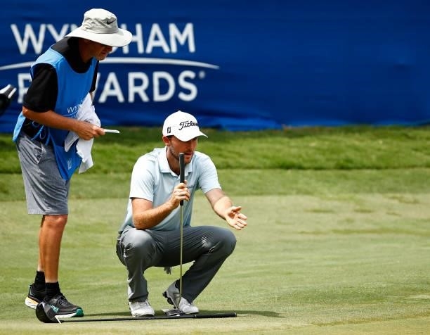 Russell Henley of the United States talks with caddie Todd Gjesvold before putting on the 18th green during the final round of the Wyndham...