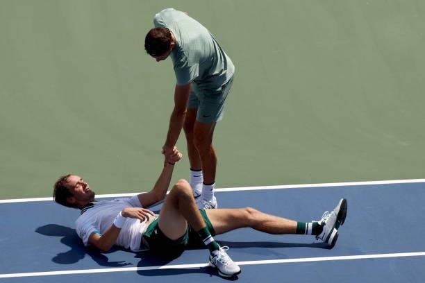 Daniil Medvedev of Russia is helped to his feet by Grigor Dimitrov of Bulgaria after falling in their match during the Western & Southern Open at...