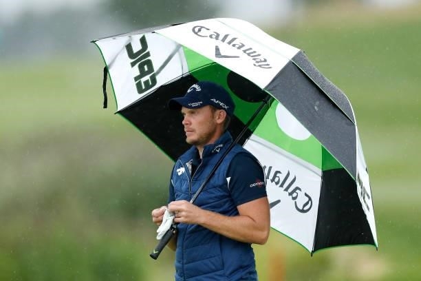 Danny Willett of England holds an umbrella as rain falls on the ninth hole during Day Two of The D+D Real Czech Masters at Albatross Golf Resort on...