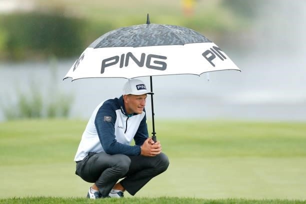 Adrian Meronk of Poland holds an umbrella on the ninth hole during Day Two of The D+D Real Czech Masters at Albatross Golf Resort on August 20, 2021...