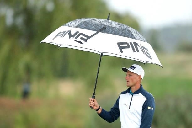 Adrian Meronk of Poland holds an umbrella on the ninth hole during Day Two of The D+D Real Czech Masters at Albatross Golf Resort on August 20, 2021...