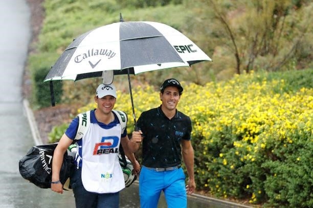 Carlos Pigem of Spain and his caddie smile as they return to the clubhouse following a suspension in play due to heavy rain during Day Two of The D+D...
