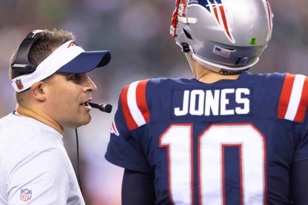Offensive coordinator Josh McDaniels of the New England Patriots talks to Mac Jones against the Philadelphia Eagles in the preseason game at Lincoln...