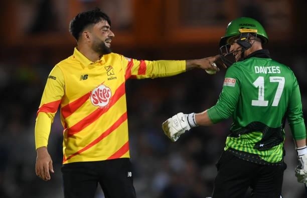 Rockets bowler Rashid Khan with the colours of the Afghanistan flag painted on his face shares a joke with Brave batsman Alex Davies during the...
