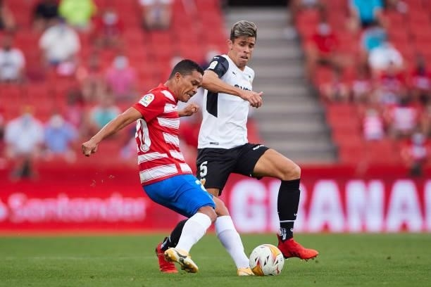 Carlos Bacca of Granada CF competes for the ball with Gabriel Paulista of Valencia CF during the La Liga Santander match between Granada CF and...