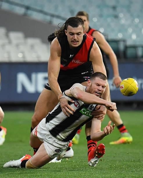 Taylor Adams of the Magpies is tackled as he handballs during the round 23 AFL match between Essendon Bombers and Collingwood Magpies at Melbourne...