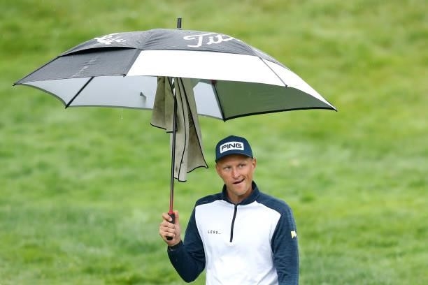 Adrian Meronk of Poland reacts as he holds an umbrella on the fourth hole during Day Four of The D+D Real Czech Masters at Albatross Golf Resort on...
