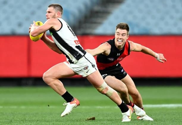 Taylor Adams of the Magpies avoids a tackle by Zach Merrett of the Bombers during the round 23 AFL match between Essendon Bombers and Collingwood...