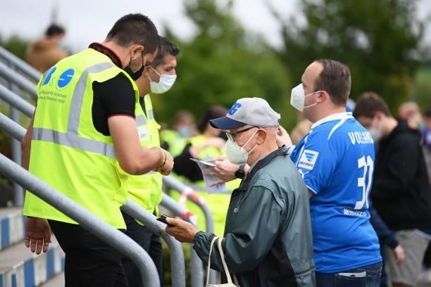 Fans wearing face masks display their tickets outside the stadium prior to the Bundesliga match between TSG Hoffenheim and 1. FC Union Berlin at...