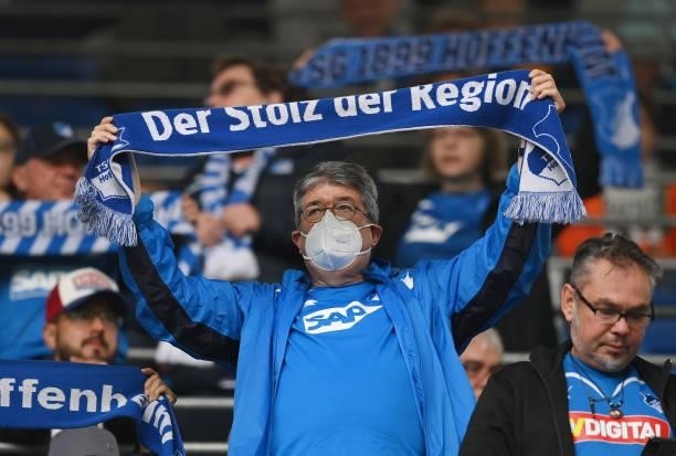 Fan wearing a face mask raises a scarf as they show their support prior to the Bundesliga match between TSG Hoffenheim and 1. FC Union Berlin at...