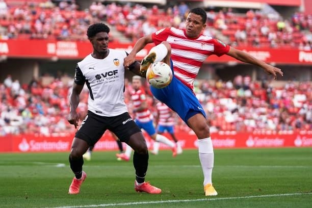 Carlos Bacca of Granada CF competes for the ball with Thierry Correia of Valencia CF during the La Liga Santander match between Granada CF and...