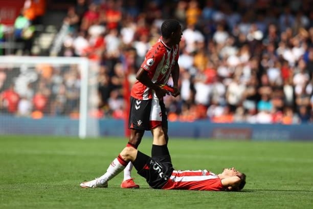 Ibrahima Diallo of Southampton assists Romain Perraud with cramp during the Premier League match between Southampton and Manchester United at St...