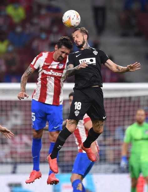 Stefan Savic of Atletico de Madrid goes for a high ball against Dario Benedetto of Elche CF during the La Liga Santader match between Club Atletico...