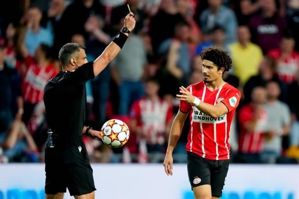 Referee Slavko Vincic shows a yellow card to Andre Ramalho of PSV during the UEFA Champions League Play-Offs Leg Two match between PSV and Benfica at...