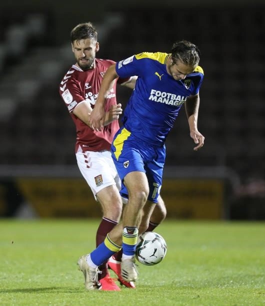 Aaron Pressley of AFC Wimbledon attempts to control the ball under pressure from Jon Guthrie of Northampton Town during the Carabao Cup 2nd Round...