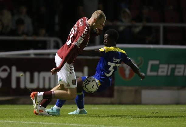 Mitch Pinnock of Northampton Town moves with the ball past Paul Osew of AFC Wimbledon during the Carabao Cup 2nd Round match between Northampton Town...