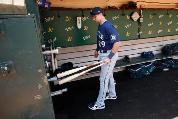 Cal Raleigh of the Seattle Mariners puts his bats away in the dugout before the game against the Oakland Athletics at RingCentral Coliseum on August...