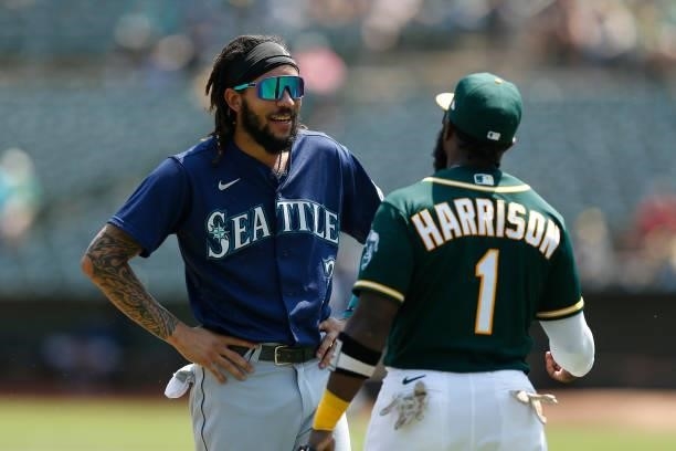 Crawford of the Seattle Mariners talks with Josh Harrison of the Oakland Athletics between innings at RingCentral Coliseum on August 24, 2021 in...
