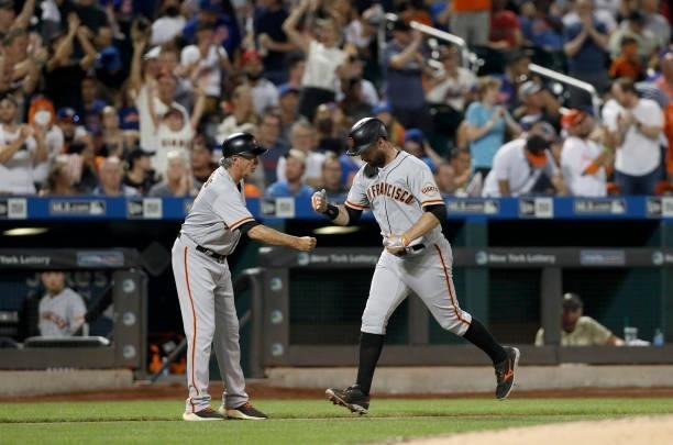 Brandon Belt of the San Francisco Giants celebrates his fourth inning home run against the New York Mets with third base coach Ron Wotus at Citi...