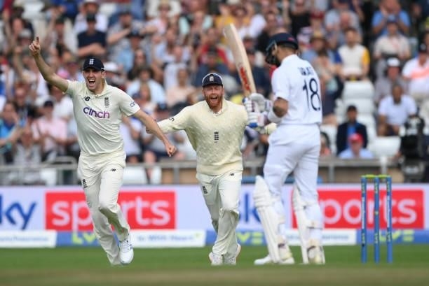 England fielders Craig Overton and Jonny Bairstow celebrate after bowler James Anderson had taken the wicket of Virat Kohli during day one of the...