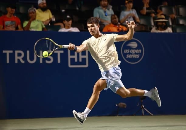 Carlos Alcaraz of Spain returns a shot to Marcos Giron in the quarterfinals of the Winston-Salem Open at Wake Forest Tennis Complex on August 26,...