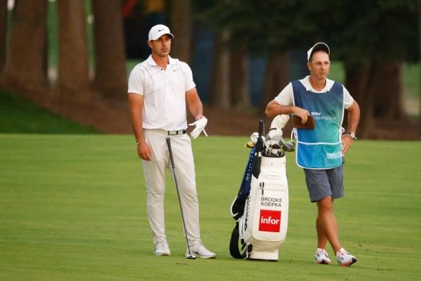 Brooks Koepka of the United States and caddie Ricky Elliott wait to play on the 16th hole during the second round of the BMW Championship at Caves...