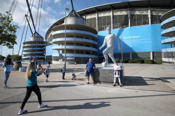 Fans pose with a statue of David Silva of Manchester City is seen outside the stadium prior to the Premier League match between Manchester City and...