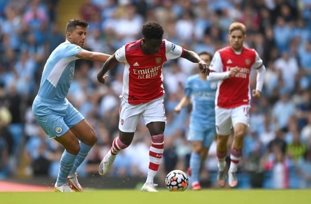 Bukayo Saka of Arsenal is challenged by Rodrigo of Manchester City during the Premier League match between Manchester City and Arsenal at Etihad...