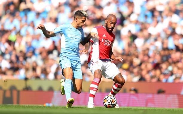 Alexandre Lacazette of Arsenal battles for possession with Joao Cancelo of Manchester City during the Premier League match between Manchester City...