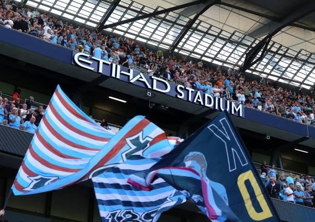 Manchester City fans wave flags ahead of the Premier League match between Manchester City and Arsenal at Etihad Stadium on August 28, 2021 in...