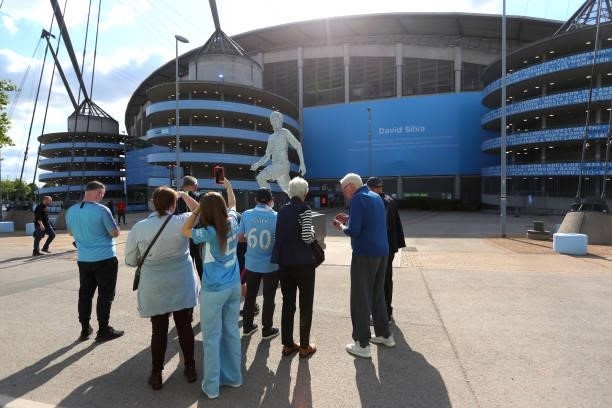 Fans take photos of the new statue of ex Manchester City player David Silva outside the Etihad Stadium during the Premier League match between...