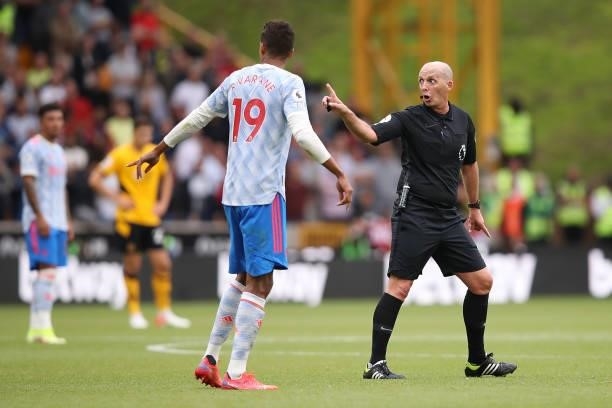 Match Referee Mike Dean interacts with Raphaël Varane of Manchester United during the Premier League match between Wolverhampton Wanderers and...