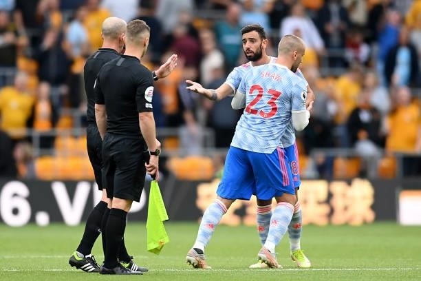 Match Referee Mike Dean interacts with Bruno Fernandes of Manchester United during the Premier League match between Wolverhampton Wanderers and...