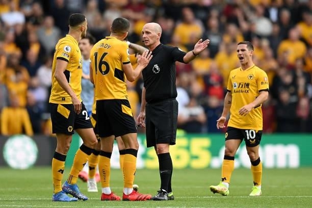Conor Coady of Wolverhampton Wanderers interacts with Match Referee Mike Dean during the Premier League match between Wolverhampton Wanderers and...