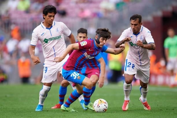 Pablo Paez 'Gavi' of FC Barcelona battles for possession with Jose Macias and Damian Suarez of Getafe CF during the La Liga Santander match between...