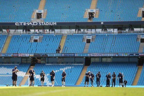 Ground staff tend to the pitch during the Premier League match between Manchester City and Arsenal at Etihad Stadium on August 28, 2021 in...