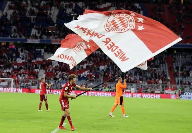 Thomas Mueller of Bayern Muenchen waves a flag as a sign of appreciation following the Bundesliga match between FC Bayern München and Hertha BSC at...