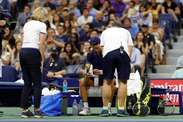 The trainers look after Holger Vitus Nodskov Rune of Denmark during a break against Novak Djokovic of Serbia during his Men's Singles first round...